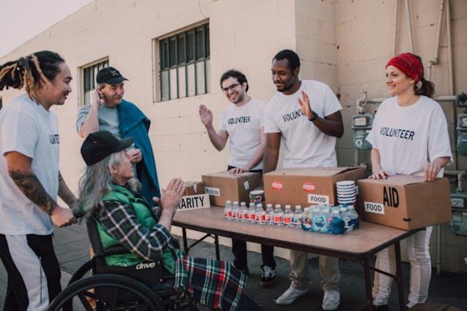 volunteers-happily-assisting-an-old-man-on-a-wheelchair-for-charity