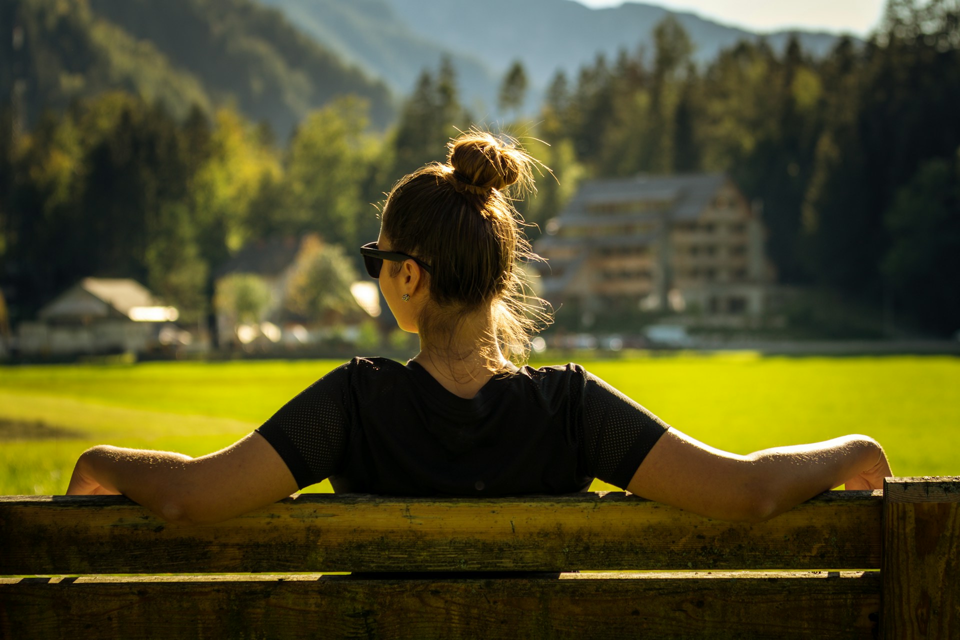 woman in black crew neck t shirt sitting on brown wooden bench during daytime