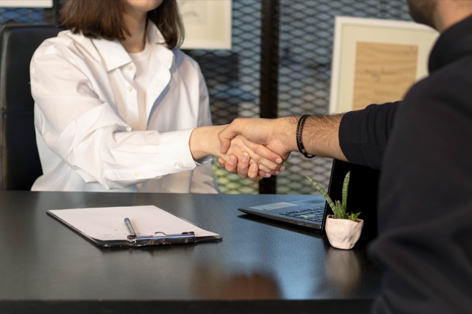 a-man-and-a-woman-shaking-hands-in-front-of-a-laptop