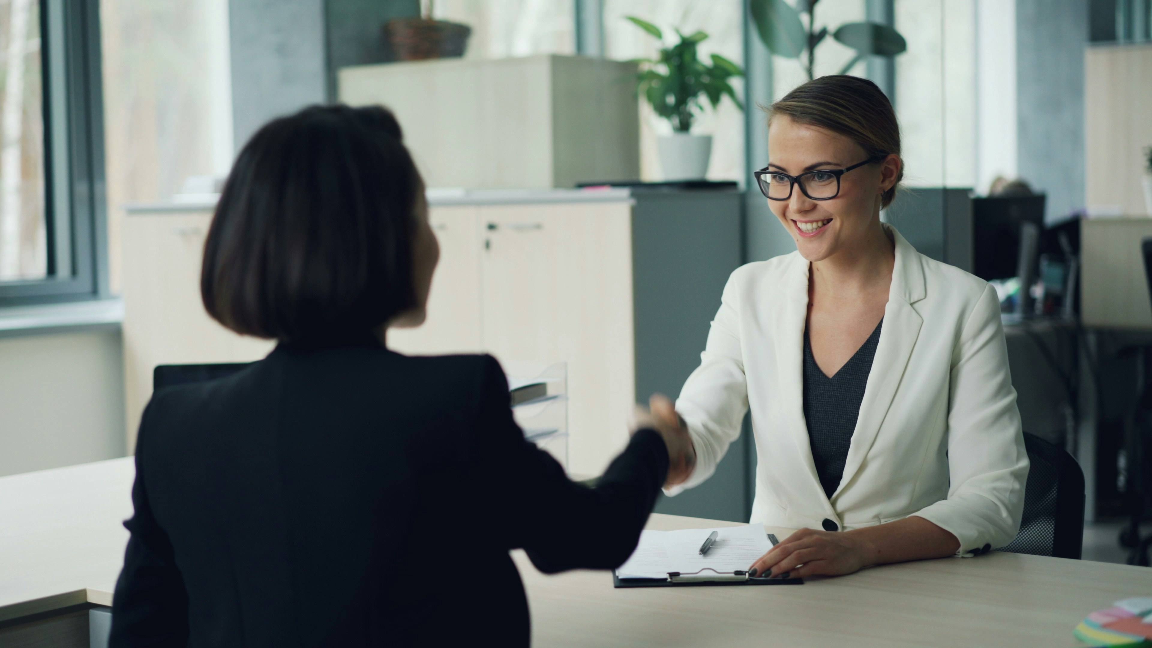 two-women-shaking-hands-across-a-desk