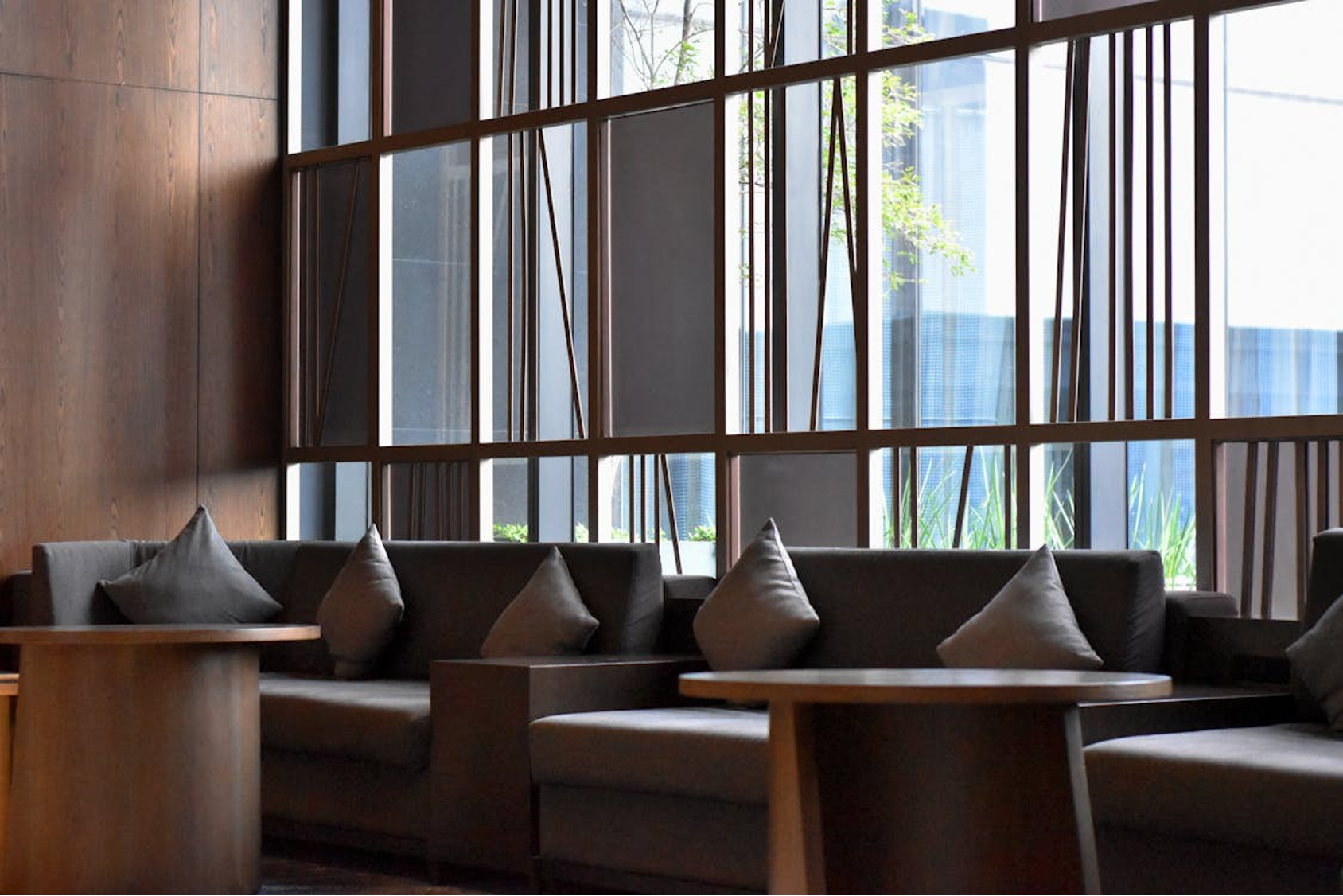 view-of-sofas-with-pillows-and-tables-standing-near-a-window-in-a-modern-building