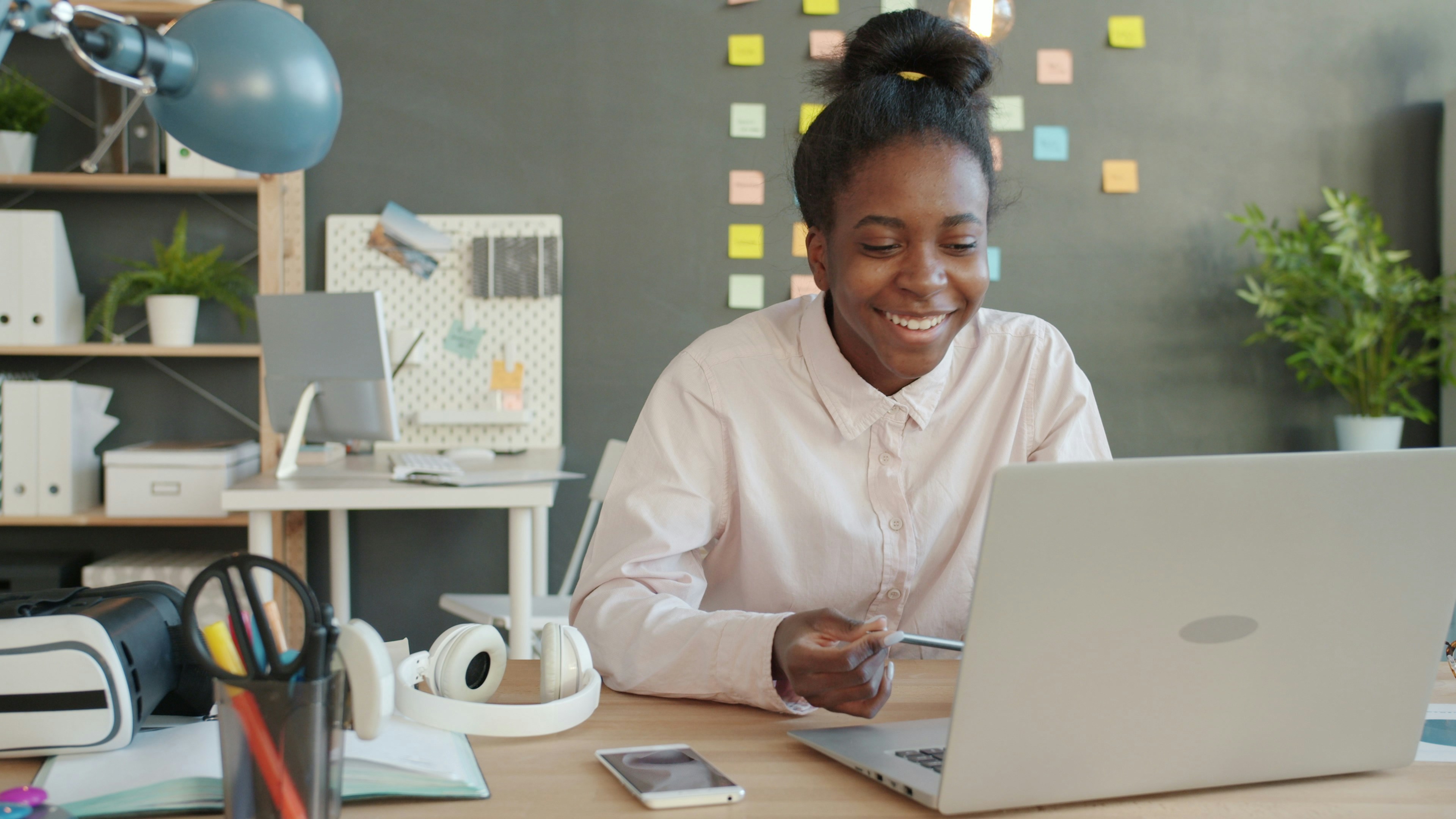 woman-smiling-while-working-on-a-laptop-at-a-desk